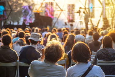Koncert muzyki filmowej. Ludzie siedzący na krzesłach przed sceną.