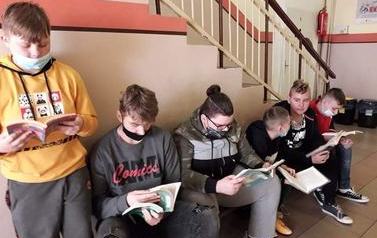 Uczniowie czytają na korytarzu szkolnym