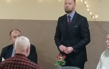Wojewoda Piotr Opaczewski przemawia, goście siedzą przy stole