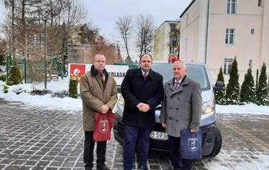 Trzech mężczyzn stojących przed  samochodem
