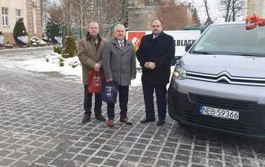 Trzech mężczyzn stojących przy samochodzie 