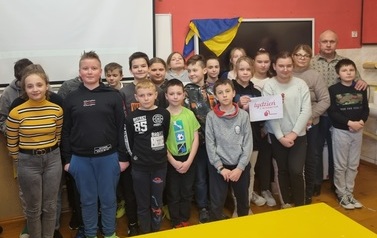 Grupa dzieci stojąca na tle tablicy w klasie lekcyjnej