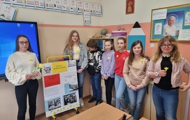 Drupa uczni&oacute;w stokjąca w klasie, prezentująca żonkile