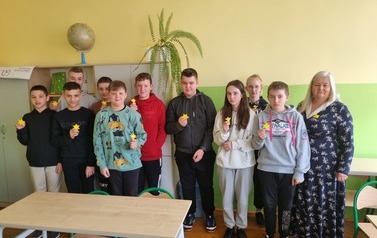 Drupa uczni&oacute;w stokjąca w klasie, prezentująca żonkile