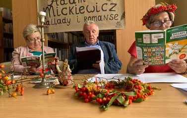 dwie kobiety i mężczyzna za stołem czytają