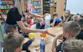 Grupa dzieci siedzi przy stole i robi gniotki